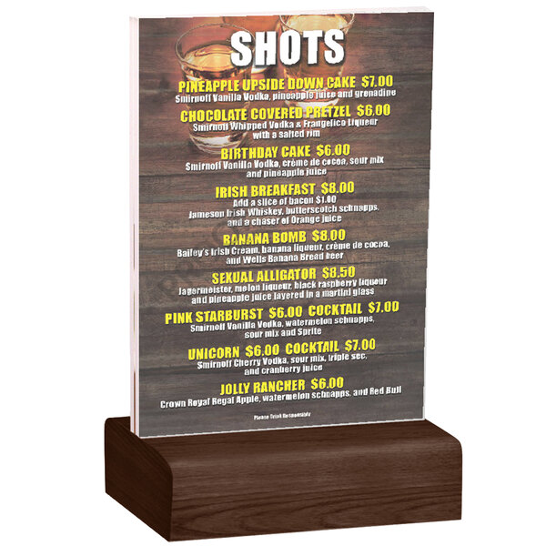 A Menu Solutions clear acrylic table tent with a solid walnut wood base holding a drink menu on a wood surface.