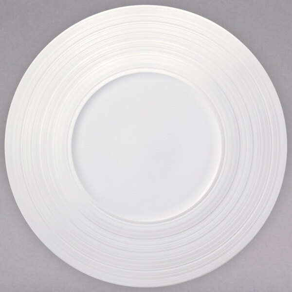 A white porcelain wide rim coupe plate with a circular pattern.