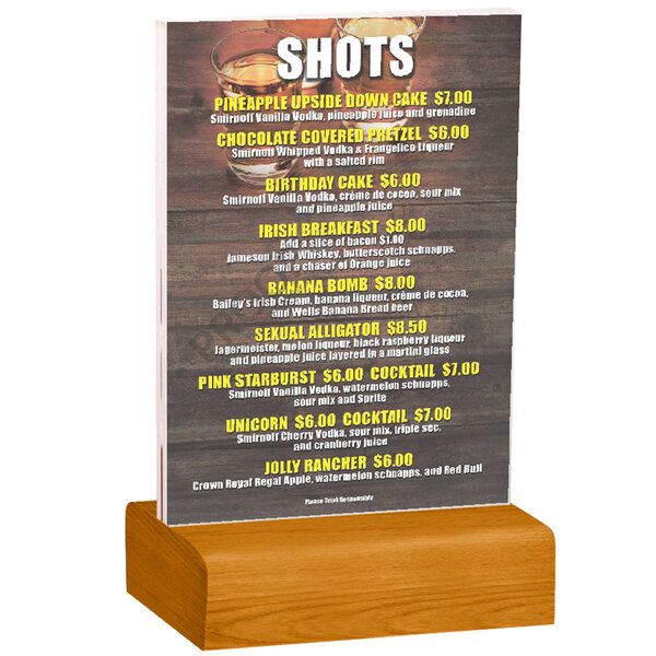 A Menu Solutions clear acrylic table tent on a solid wood stand holding a drink menu.