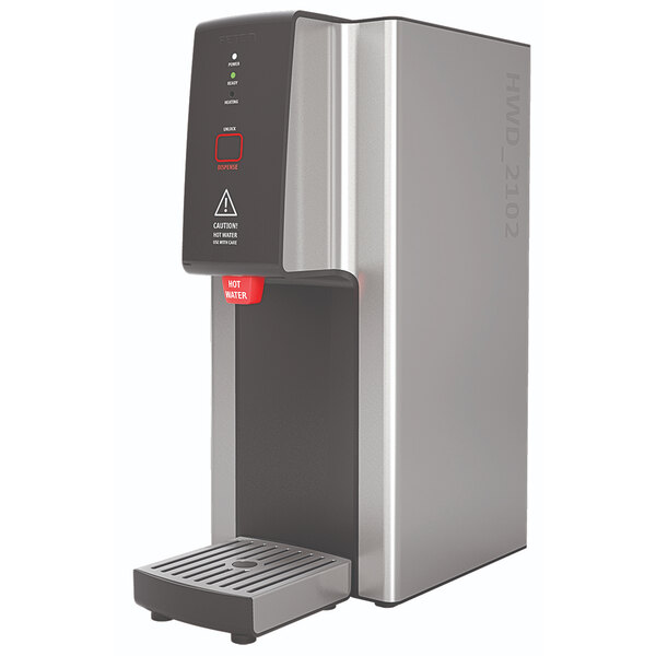 A silver and black Fetco hot water dispenser with a black cover and red push-button controls.