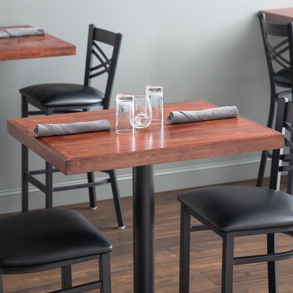 A Lancaster Table & Seating butcher block table with glasses and napkins on it.
