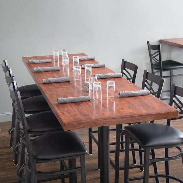 A Lancaster Table & Seating butcher block table with chairs, glasses, and napkins on it.