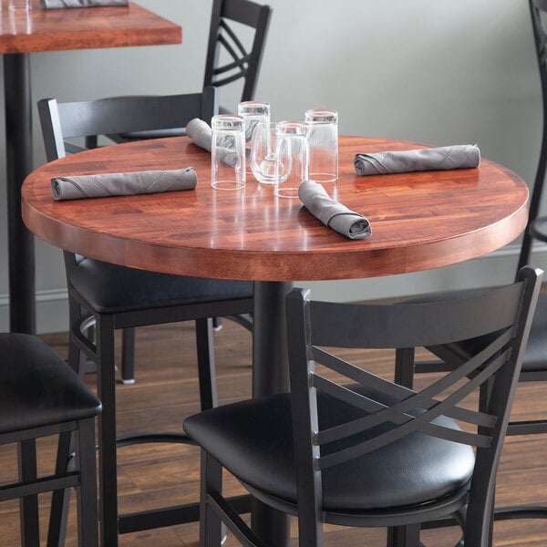A Lancaster Table & Seating mahogany wood table top with glasses and napkins on it.