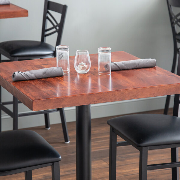 A wood table top with glasses and napkins on it.