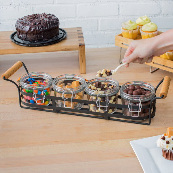 A Tablecraft condiment caddy with open glass jars holding chocolate chips and chocolate balls.