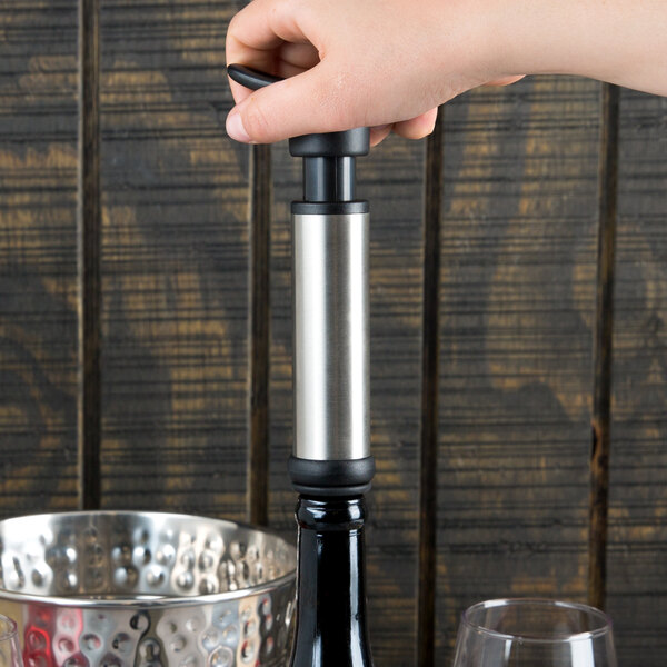 A person using the Franmara VinoVac wine saver system to pour wine into a glass.