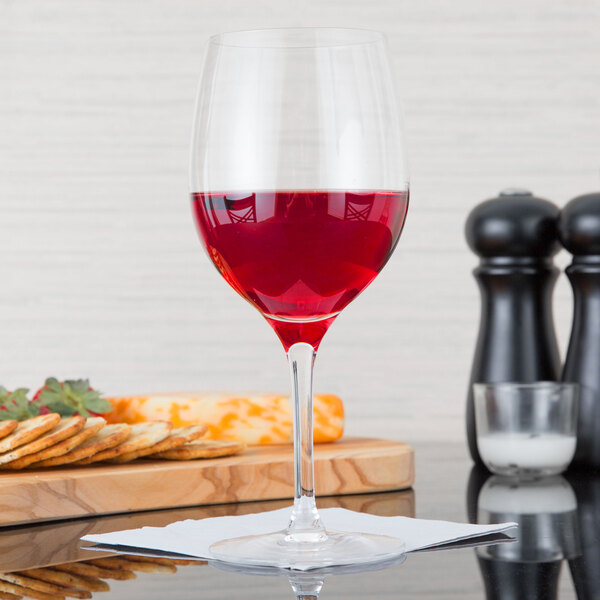 A Stolzle all-purpose wine glass filled with red wine on a table.