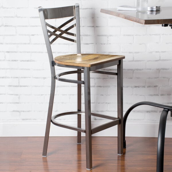 A Lancaster Table & Seating metal bar stool with a driftwood seat.