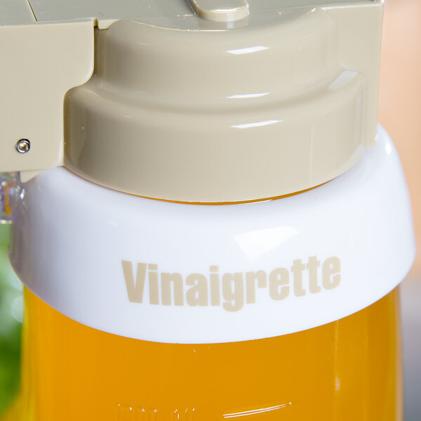 A close up of a Tablecraft white plastic salad dressing dispenser collar with beige lettering.