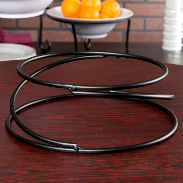 An American Metalcraft wrought iron riser with a bowl of oranges on it.