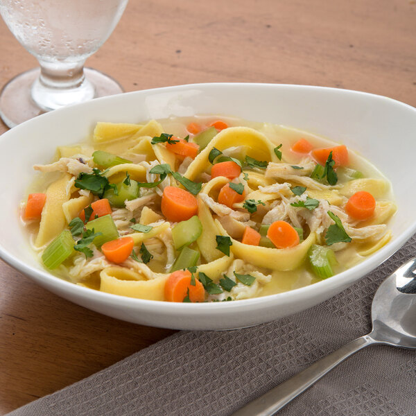 A bowl of chicken noodle soup with extra wide egg noodles and vegetables.