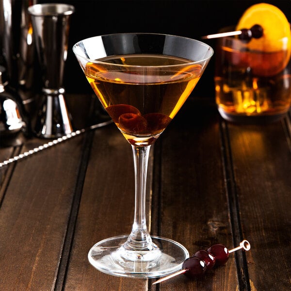 A martini glass with Fabbri Amarena cherries on a wooden surface.