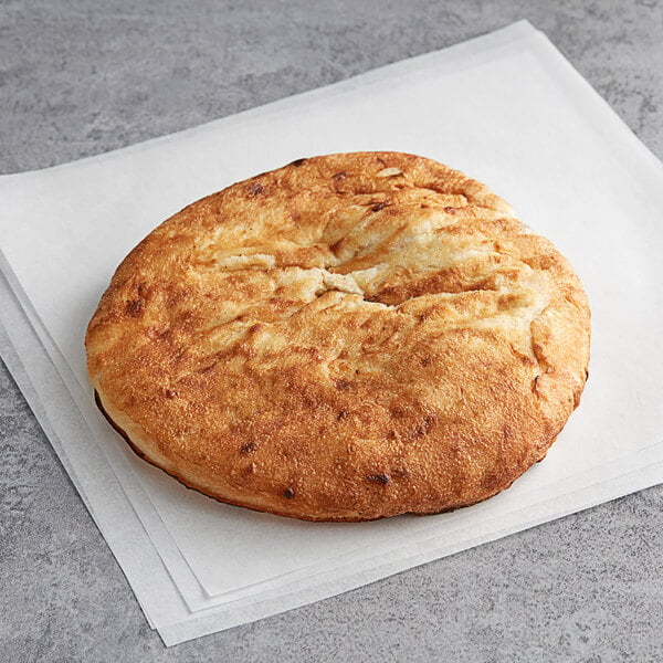 A round brown Father Sam's Bakery white pita bread on a white surface.