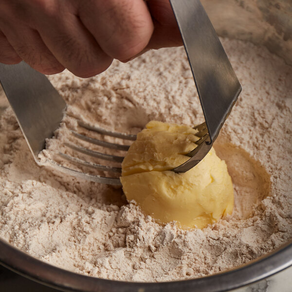A hand using a fork to cut Crisco butter shortening over dough.