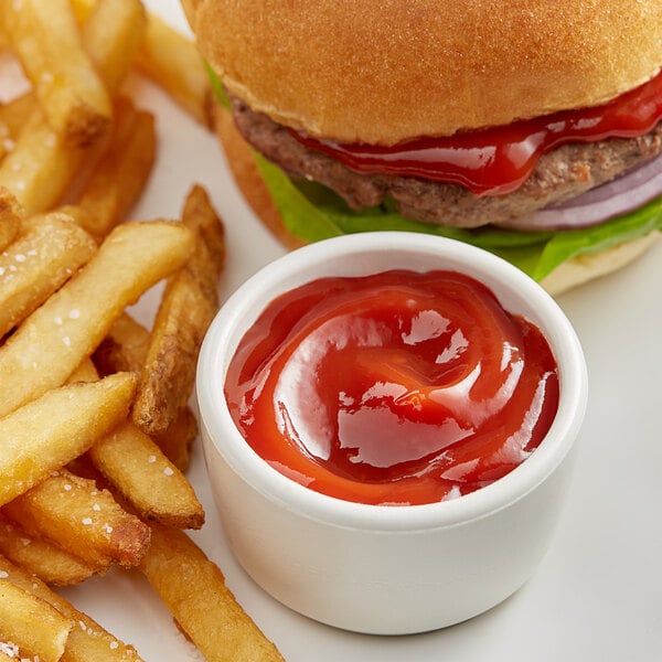 A hamburger and French fries with Heinz ketchup on a plate.