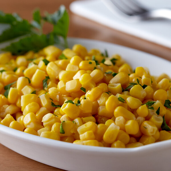 A bowl of Del Monte Golden Sweet whole kernel corn on a table.