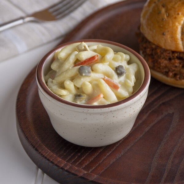 A bowl of Spring Glen Fresh Foods Amish macaroni salad on a table with a hamburger.