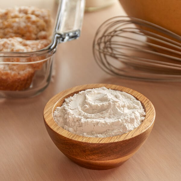 A bowl of cake flour next to a bowl of muffins.