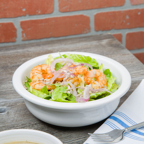 A close up of a Fiesta White China serving bowl filled with salad and shrimp.