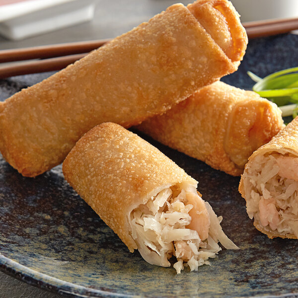 A close up of a plate of fried shrimp egg rolls.