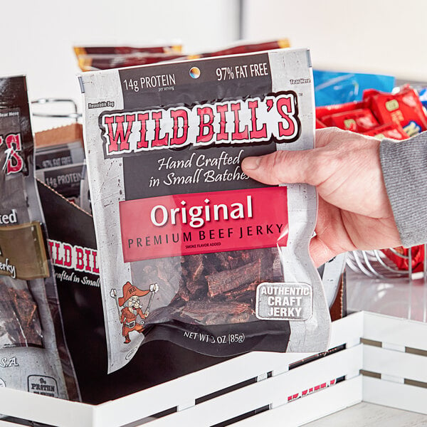 A hand holding a package of Wild Bill's Hickory Smoked Tender Tips beef jerky.