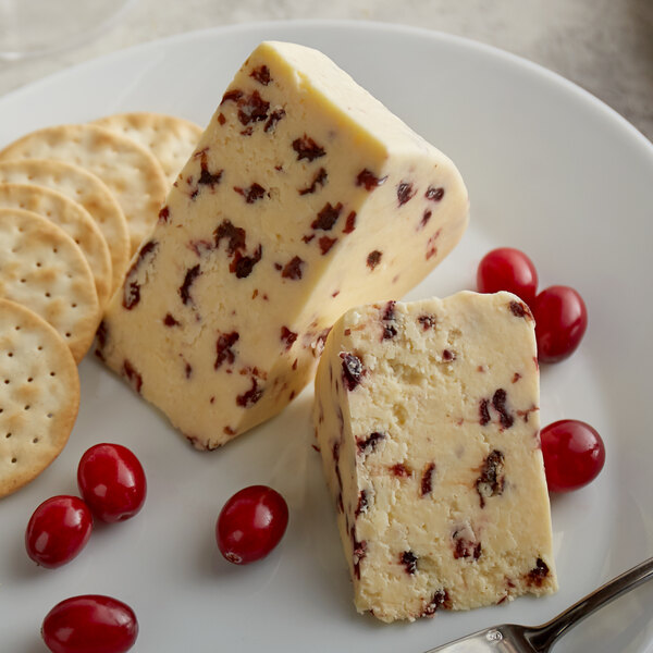 A plate with a piece of Long Clawson Dairy White Stilton Cheese with Cranberries and crackers.