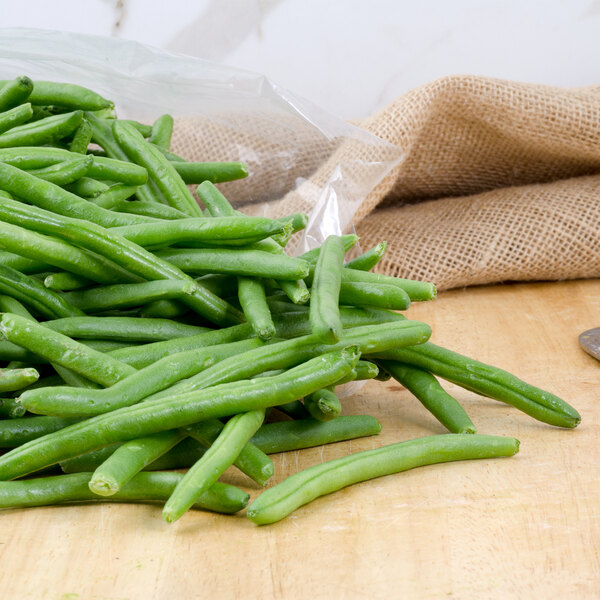 A pile of snipped green beans on a cutting board.