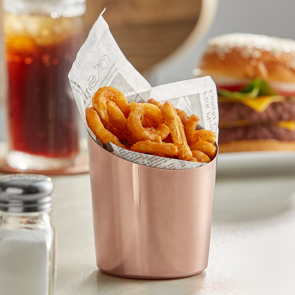 An Acopa stainless steel cup filled with French fries on a table.