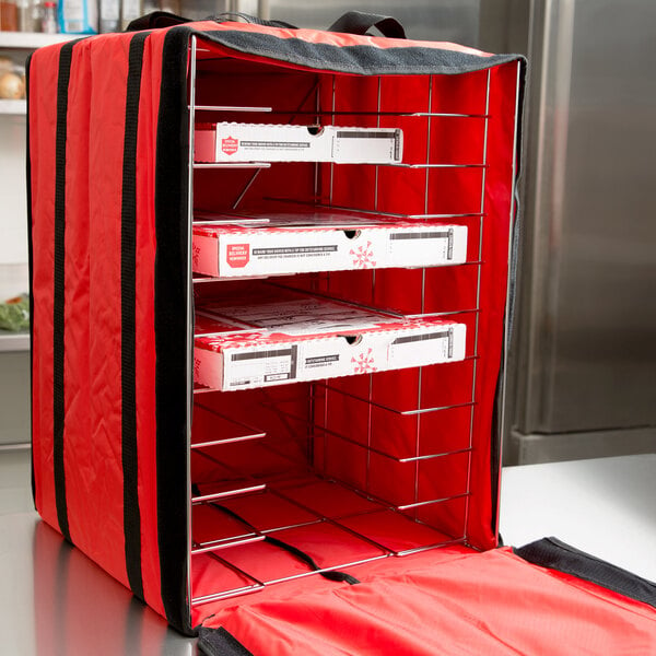 A red nylon American Metalcraft delivery bag with shelves inside holding pizza boxes.
