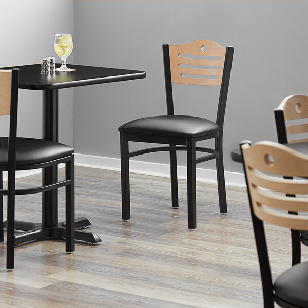 A Lancaster Table & Seating black bistro chair with a black vinyl seat and natural wood back.