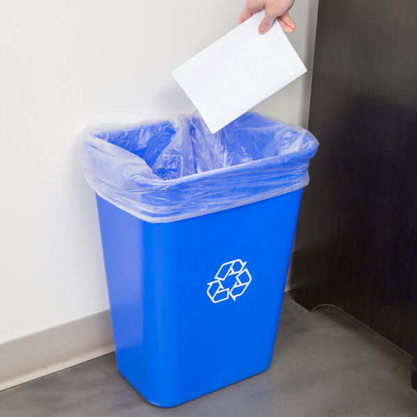 A hand putting paper into a blue Continental recycling bin.