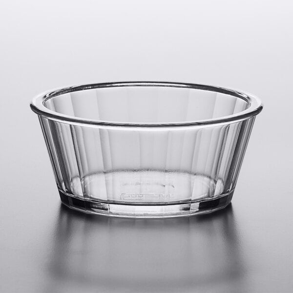 A clear plastic fluted ramekin on a white surface.