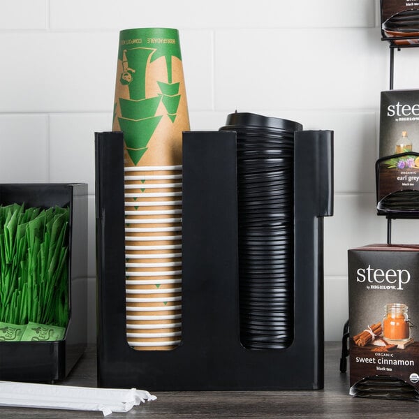 A black Choice 2-section countertop cup and lid organizer holding paper cups on a counter.
