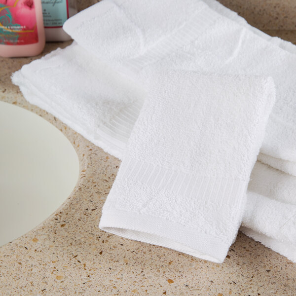 A stack of white Oxford Belleeza wash cloths on a counter.