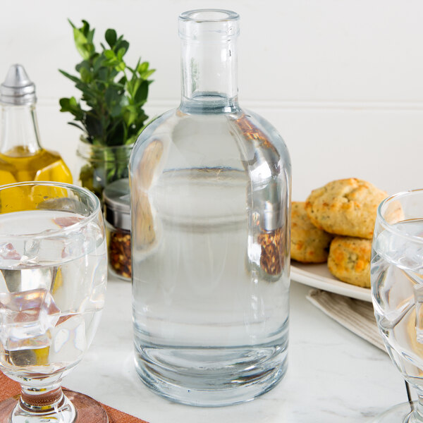 A close up of an Anchor Hocking Stockholm glass bottle next to a glass of water.