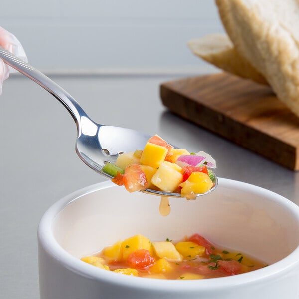 A Mercer Culinary stainless steel perforated bowl plating spoon filled with fruit.