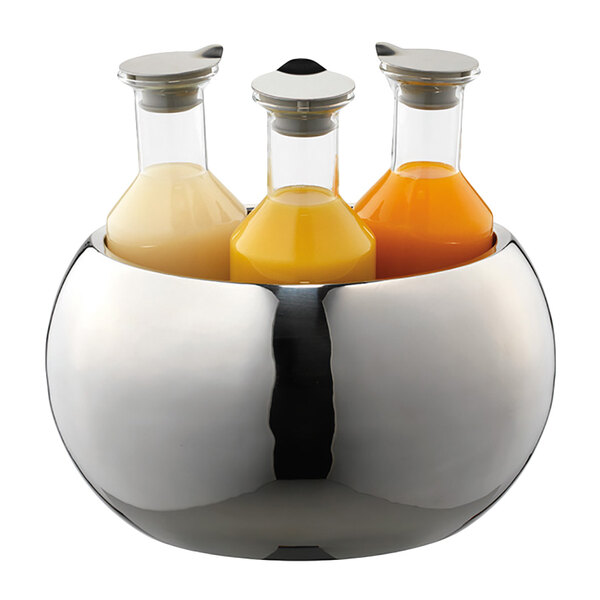A Frilich polished stainless steel bowl filled with three carafes of yellow liquid on a counter.