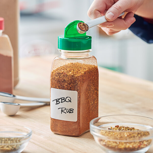 A person pouring spice from a jar into a bowl.