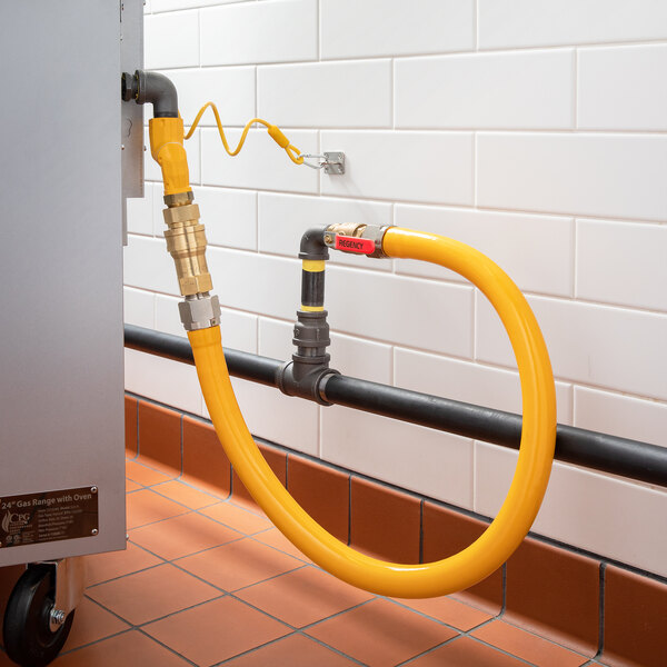A yellow gas hose with a swivel connector connected to a metal pipe.