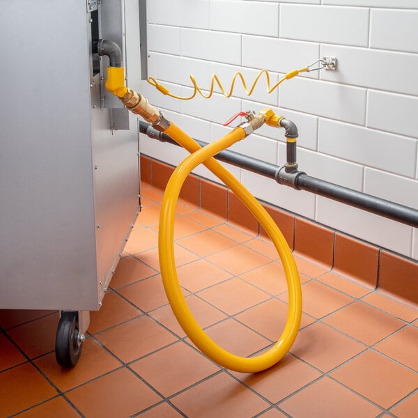 A yellow hose connected to a metal pipe with a white rectangular object on it.