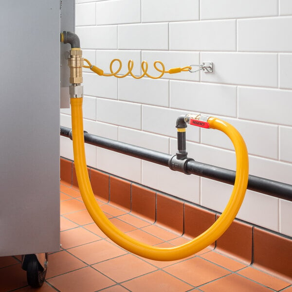 A yellow Regency gas connector hose connected to a metal pipe.