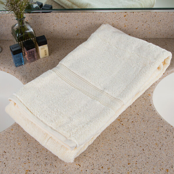 An Oxford Vicenza Avorio white bath towel with a dobby border on a white counter.
