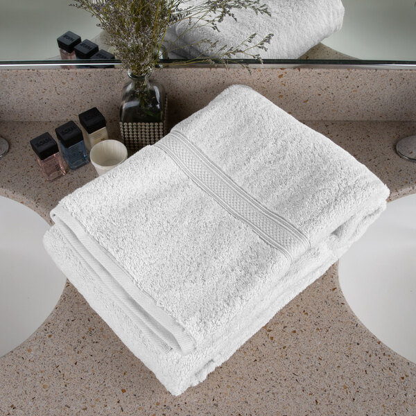 A white Oxford Vicenza bath towel on a white counter top.