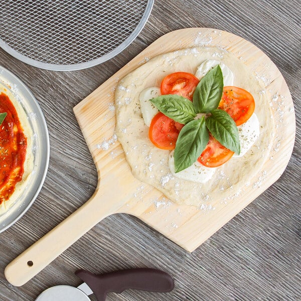 Pizza dough made with Regal 10 lb. 00 Pizza Flour on a wooden board with tomatoes and basil.