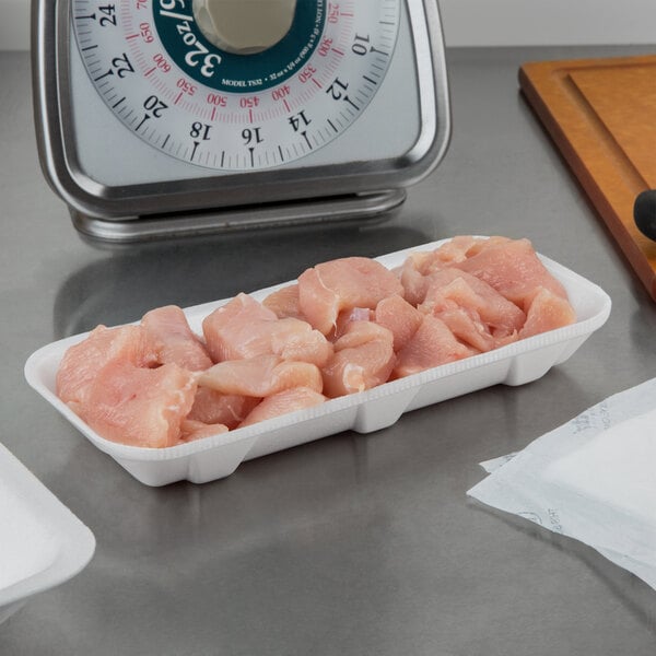 A white foam CKF meat tray on a counter with raw chicken.