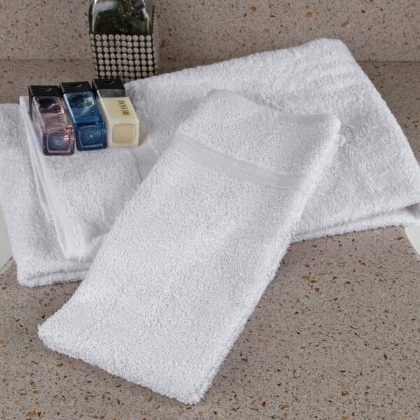 A group of white Oxford Bronze hand towels on a counter.