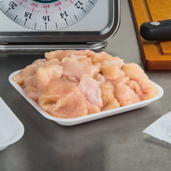 A white foam CKF meat tray holding raw chicken on a counter.