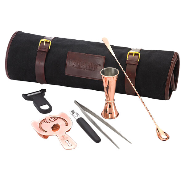 A Barfly copper-plated cocktail kit on a table with a drink shaker and bar utensils.