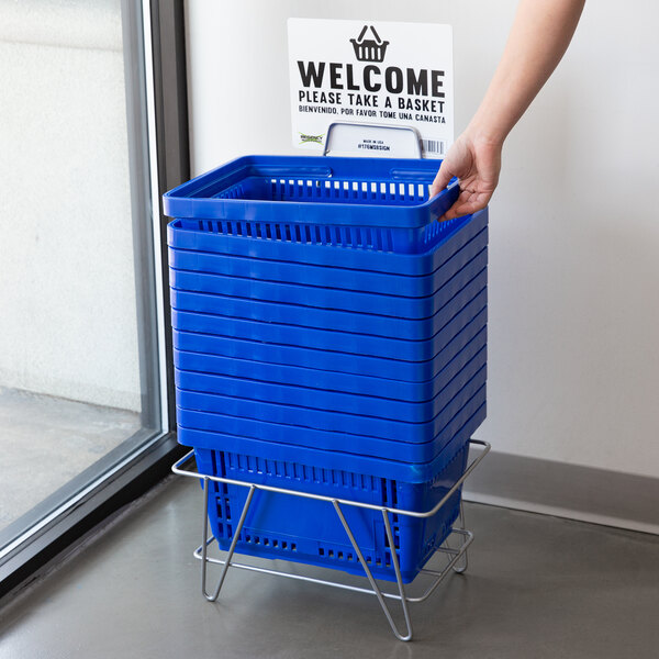 A person holding a blue Regency shopping basket with a welcome sign.