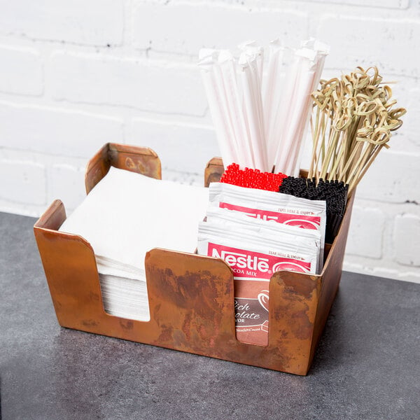 An American Metalcraft copper bar caddy with napkins and straws inside.